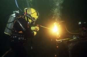 A commercial diver cutting through metal